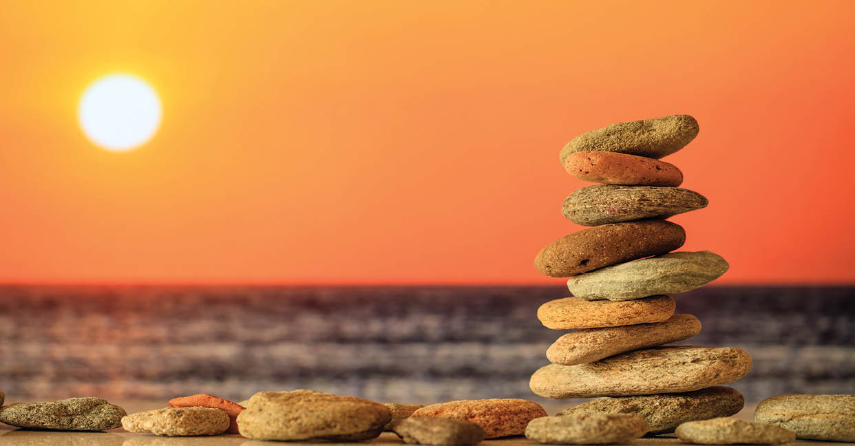 Zen stones stacked on sea background at sunset