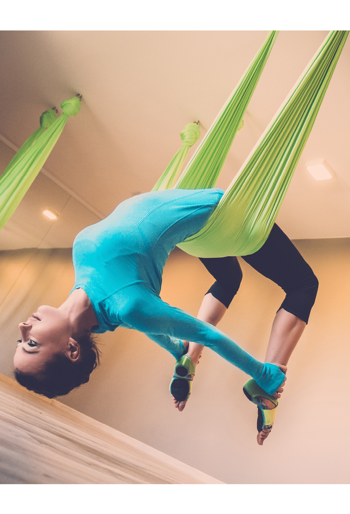 Young woman performing antigravity yoga exercise 
